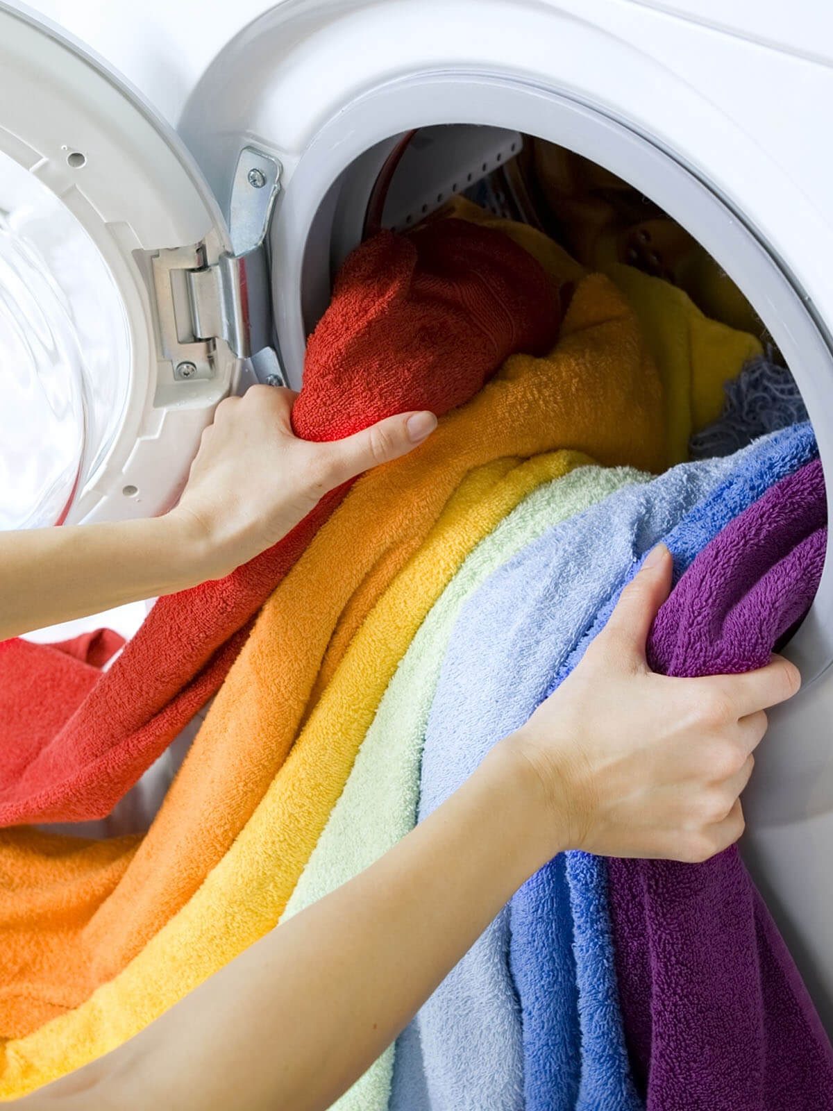 imagem de mulher tirando roupas coloridas e limpas da maquina de lavar roupas da porte da frente da máquuina.